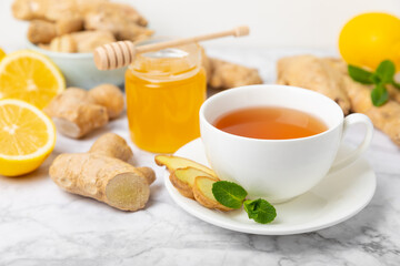 Cup of hot ginger tea with slices of ginger root on wooden background. Warming drink. Alternative medicine. Tea with honey, lemon, ginger and mint. Space for text. Copy space