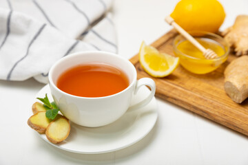 Cup of hot ginger tea with slices of ginger root on wooden background. Warming drink. Alternative medicine. Tea with honey, lemon, ginger and mint. Space for text. Copy space