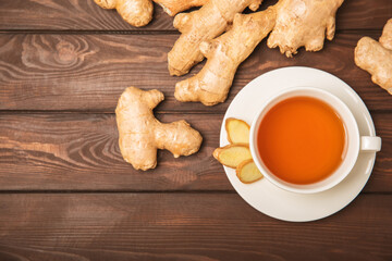 Cup of hot ginger tea with slices of ginger root on wooden background. Warming drink. Alternative medicine. Tea with honey, lemon, ginger and mint. Space for text. Copy space