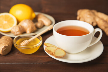 Cup of hot ginger tea with slices of ginger root on wooden background. Warming drink. Alternative medicine. Tea with honey, lemon, ginger and mint. Space for text. Copy space