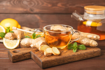 Cup of hot ginger tea with slices of ginger root on wooden background. Warming drink. Alternative medicine. Tea with honey, lemon, ginger and mint. Space for text. Copy space