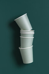 Disposable light green paper cups on a dark green top view, mockup. Sustainable lifestyle