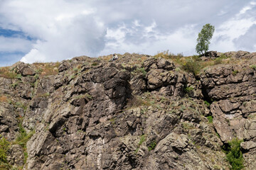 Kamensk-Uralsky, Sverdlovsk region, Russia - August 13, 2024: A man and a woman are sitting on the edge of a large mountain and admiring the views. Howler Threshold on the Iset River