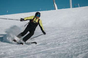 A skilled skier performing dynamic turns on a snowy slope under clear blue sky. The scene captures the excitement and energy of skiing in a picturesque winter landscape.