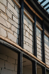 Close-up of a rustic white brick wall with black window frames, showcasing architectural details and textures. The image evokes a sense of vintage charm and classic design.
