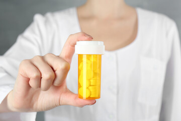 Doctor holding medical bottle of antibiotic pills, closeup