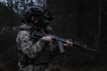 Fototapeta premium Soldier in a gas mask with night vision device in a post-apocalyptic forest.