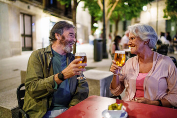 Happy senior couple enjoying beers at outdoor cafe