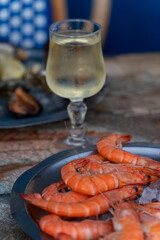 Big red boiled shrimps and other shell mussels with a glass of white wine on the outdoor terrace on a French Riviera. Classic healthy Mediterranean holiday and vacation lunch or dinner. 