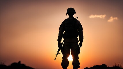 Fototapeta premium Silhouette of a soldier standing with a rifle at sunset.