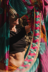 Fototapeta premium Close-up portrait of Indian woman in traditional saree clothes dancing on the nature with the ocean on background. Indian festival costume. Concept of solo tourism and travel to India.