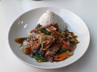 Asian spicy sweet and sour beef stir-fry with colorful vegetables and white rice, served on plate, vibrant oriental cuisine concept, delicious and fresh meal close-up.