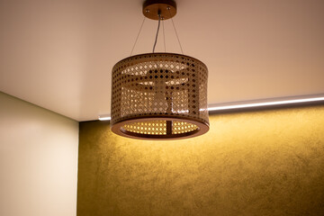 Luminária de teto feito de bambu com perfil de led com cor quente ao fundo. 