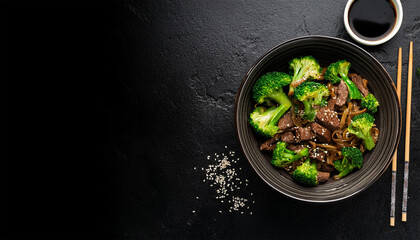 flat lay of broccoli and beef stir fry with soy sauce in bowl on black concrete background with copy space delicious asian dish