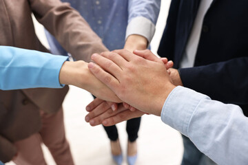 Teamwork. Group of people joining hands together indoors, closeup