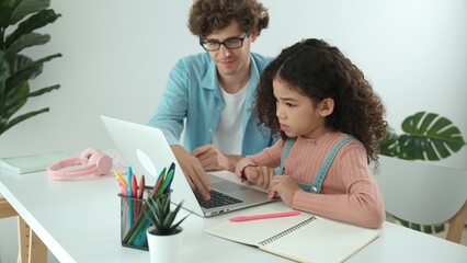 American daughter learning to coding and writing engineering prompt while positive smart father studying together and pointing at laptop screen to show programing code or system with care. Pedagogy.