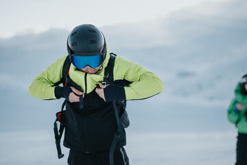 A person in outdoor winter gear adjusts his equipment before skiing in snowy mountains.