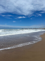 empty city beach on a sunny day, blue sky and small waves
