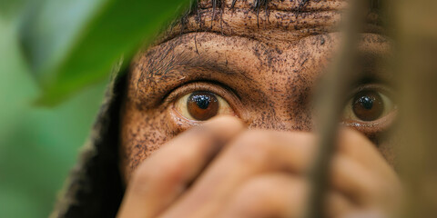 Obraz premium Close-up Photograph of a Dirt-Covered Person's Eyes Partially Hidden Behind Foliage