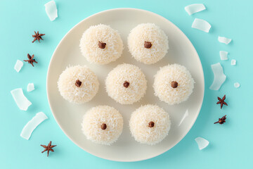 Beijinho coconut sweets with star anise on white plate over blue background