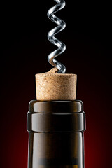 A closeup of a red wine bottle opening, using a classic corkscrew.