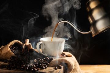 Pour black coffee into a coffee cup There are roasted coffee beans on the table. with a black background and dark colors