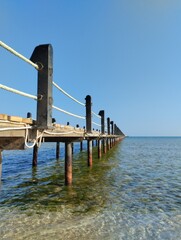  long pontoon bridge extending into the sea, open sea, sea coast, deserted beach without people, bridge on piles