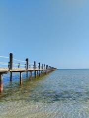  long pontoon bridge extending into the sea, open sea, sea coast, deserted beach without people, bridge on piles