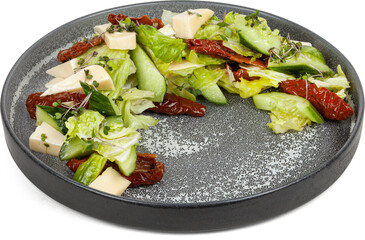 Salad with cheese and sun-dried tomatoes on a plate on a white background