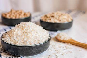 A bowl of white rice in focus with oats and chickpeas blurred in the background, showcasing a clean and rustic food arrangement