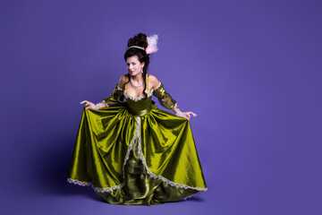 Obraz premium Elegant woman in a green baroque dress posing on purple background, reflecting historical style