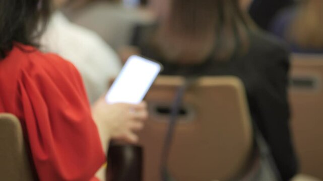 A woman is sitting in a chair with a cell phone in her hand. Concept of modern technology and the prevalence of smartphones in our daily lives