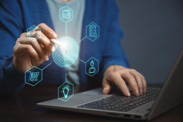 A person is working on a laptop, interacting with virtual icons on the screen. The icons represent various functions and tools.