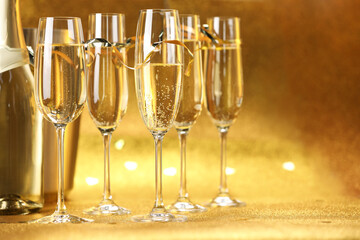 Champagne, bottle and ice bucket on golden background, closeup. Space for text