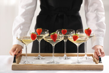 Waiter holding tray with glasses of champagne indoors, closeup