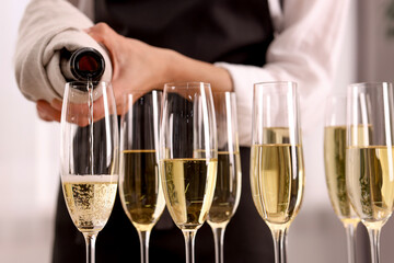 Waiter filling glasses with champagne indoors, closeup