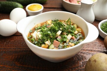 Delicious okroshka soup and ingredients on wooden table, closeup