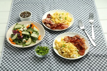 Tasty brunch. Delicious scrambled eggs, bacon and salad served on white wooden table