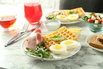 Tasty brunch. Boiled egg, Belgian waffle, arugula and ham on white marble table