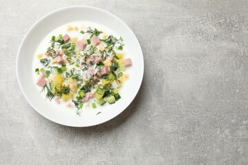Delicious okroshka soup in bowl on grey textured table, top view. Space for text
