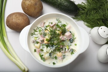 Delicious okroshka soup in bowl and ingredients on white table, flat lay