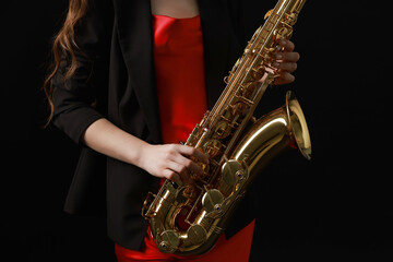 Obraz premium Professional musician with saxophone on black background, closeup