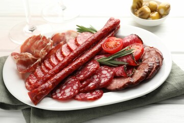 Different smoked sausages slices served on white wooden table, closeup