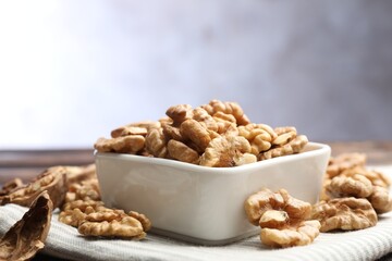 Peeled walnuts in bowl on table against light background, closeup