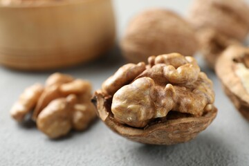 Fresh walnuts with shells on gray table, closeup. Space for text
