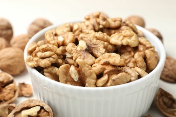 Peeled walnuts in bowl on light table, closeup