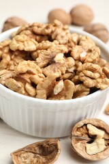 Peeled walnuts in bowl on light table, closeup
