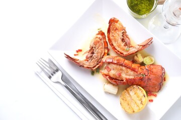 Delicious lobster tails with lemon and green onion on white table, flat lay. Space for text