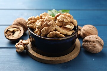 Fresh walnuts in bowl on blue wooden table, closeup
