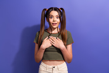 Excited teenager with expressive face and ponytails standing against violet background